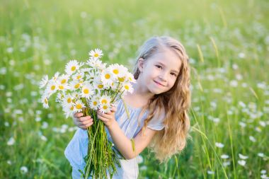 Papatya alanındaki sevimli küçük gülümseyen kız 