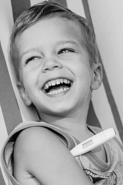 Glad skrattande liten pojke mäta temperatur — Stockfoto