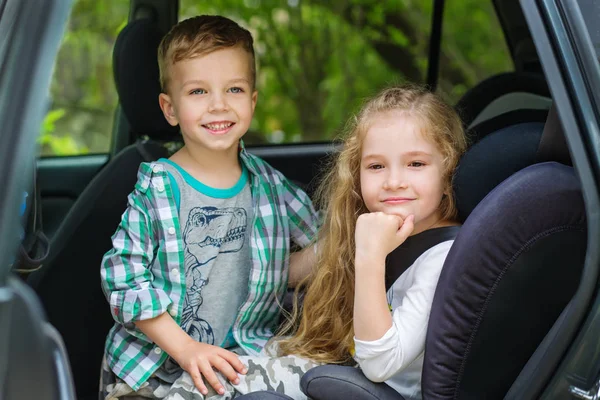 Mignon fille et garçon assis dans la voiture — Photo
