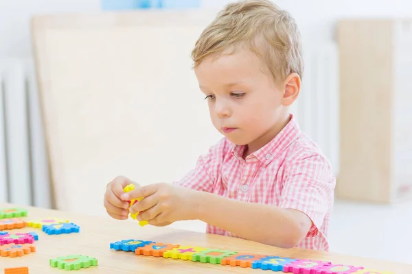 Pequeño niño lindo enfocado recoge rompecabezas — Foto de Stock