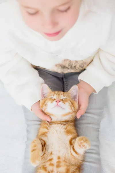 Niedliches kleines Mädchen hält ein Kätzchen auf einer Ingwerhand — Stockfoto