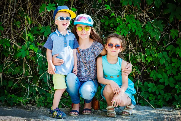 Parkta oynayan üç mutlu gülümseyen çocuk