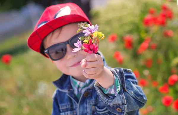 Смешной маленький мальчик в солнечных очках с букетом — стоковое фото