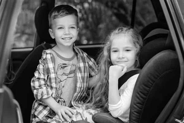 Linda chica y niño sentado en el coche —  Fotos de Stock