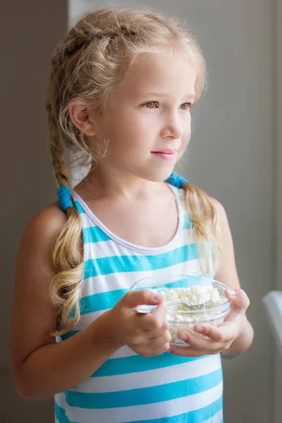 Милая маленькая девочка ест творог — стоковое фото
