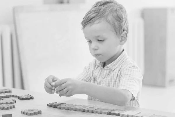 Focused cute little child collects puzzles — Stock Photo, Image