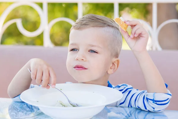 Счастливый маленький мальчик ест суп в кафе — стоковое фото
