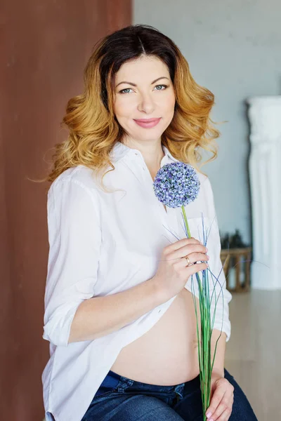 Close-up van zwangere vrouw, In een wit shirt en spijkerbroek — Stockfoto