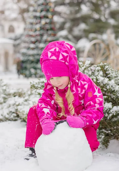 Linda niña esculpe un muñeco de nieve — Foto de Stock