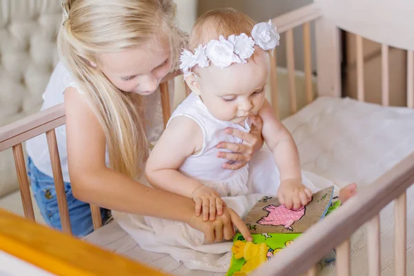 La hermana mayor le muestra el libro a la hermanita — Foto de Stock