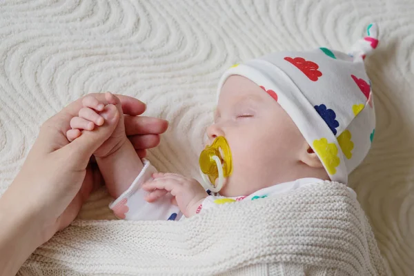 Neugeborenes schläft mit fürsorglicher Berührung der Hände der Mutter — Stockfoto