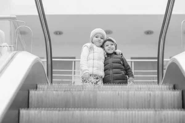 Glückliche kleine Kinder auf einer Rolltreppe — Stockfoto