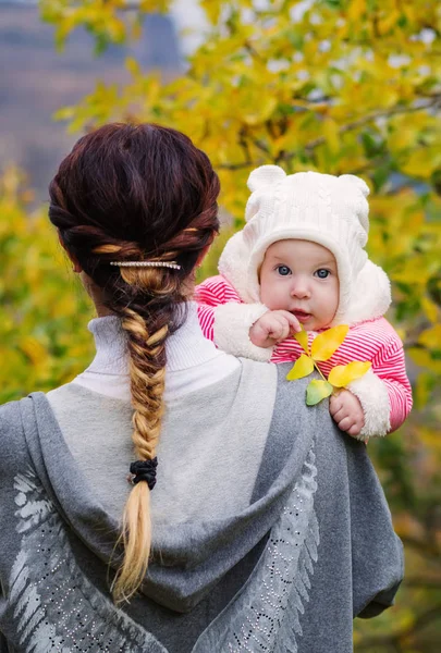 Eine junge glückliche Mutter hält ihre kleine Tochter auf der Schulter — Stockfoto