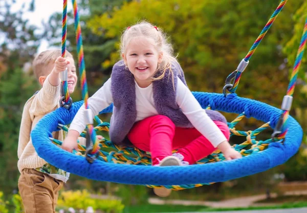 Twee gelukkige kleine kinderen plezier op een schommel — Stockfoto