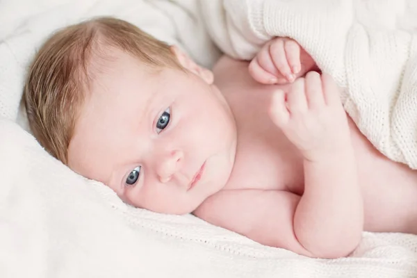 Новорожденный ребенок лежит под вязаным хлопком — стоковое фото