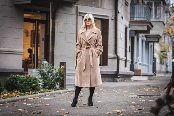 Mladá krásná blondýnka v podzimním kabátě stojí na městské ulici. Jemné soustředění. Módní koncept. Stock Fotografie