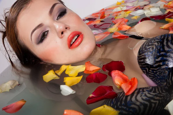 Красива дівчина з макіяжем лежить у ванній з квітами — стокове фото