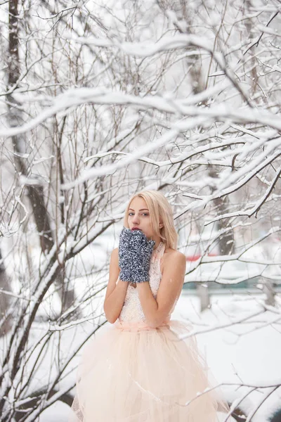 Красива молода блондинка в білій сукні позує в засніженому зимовому парку — стокове фото