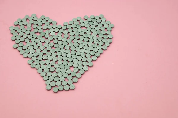 Doces dispersos em forma de coração em um fundo rosa — Fotografia de Stock