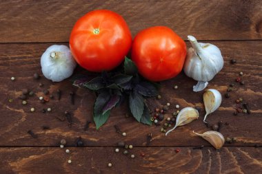 Kırmızı ve olgun domatesler, dağınık baharatlar biber ve karanfil ve kahverengi ahşap arka plan manzaralı bir demet kekik.