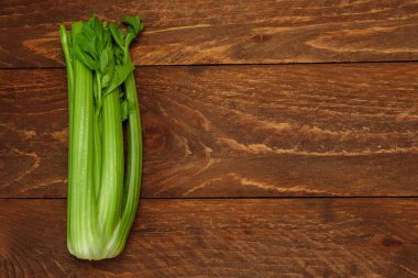  Bir grup yeşil kereviz sapı kahverengi ahşap arka plan görünümünde ve metin için boş alanı var.