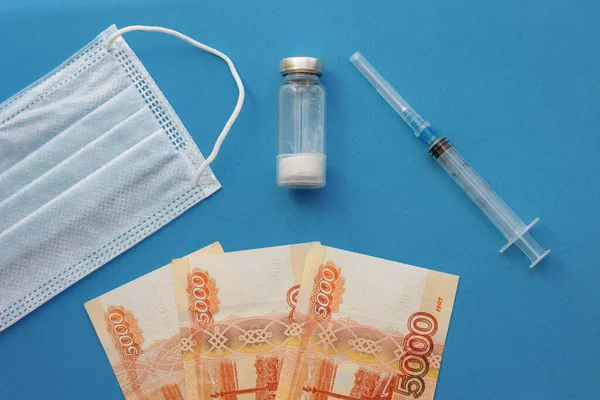  Tek kullanımlık tıbbi maske, bir şişe ilaç, bir şırınga ve Rus rublesinin kağıt banknotları.