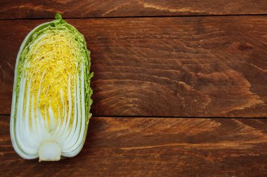 Yeşil Çin lahanası kahverengi ahşap mutfak masasının üstünde ikiye bölünmüş.