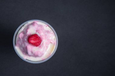 Bir bardak çilekli milkshake ya da siyah masada krema