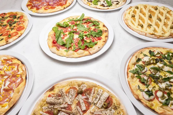 Beyaz mermer masada çeşitli pizzalar.