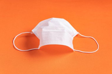 Minimalist turuncu arka plan üzerinde cerrahi maske
