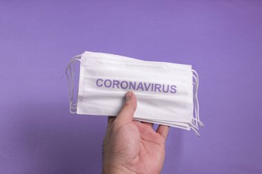 Adamın eli cerrahi maske tutuyor.