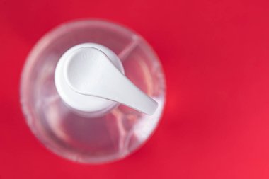 Kırmızı arka planda alkol jeli olan konteyner.