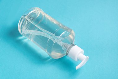 Açık mavi zemin üzerinde alkol jeli olan konteynır