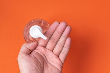 Turuncu arka planda alkol jeli olan bir adam el ele veriyor.