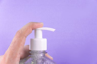 Açık mavi arka planda alkol jeli olan bir adam el ele veriyor.