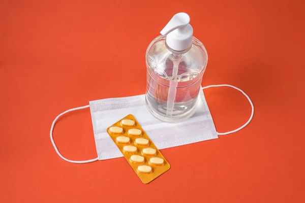 Alcohol gel container, surgical mask, medicine on the red background