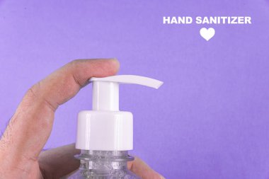 Açık mavi arka planda alkol jeli olan bir adam el ele veriyor.