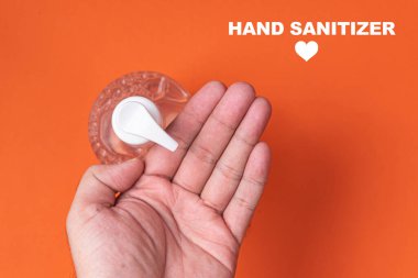 Turuncu arka planda alkol jeli olan bir adam el ele veriyor.