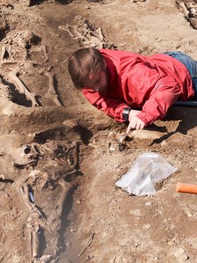 Archaeologist carefully digs up human bones clipart