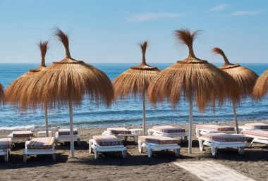 Şemsiye ve şezlonglar turistler için bir plajda.