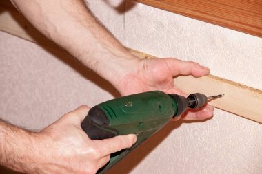 Man works with cordless screwdriver on a wall in the house