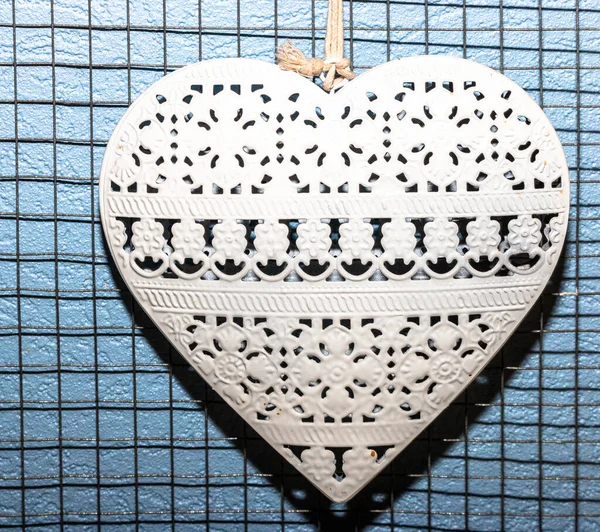 white metal heart on blue wire background