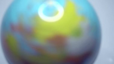 Okul küresi. Bir adam küre üzerinde döner ve onu gösterir. Dünya 'nın küresel şekli. Minyatür gezegen. Sınıfta toz parçacıkları olan bir dünya. Avrupa