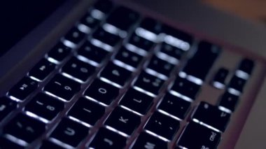 Karanlık bir odada dizüstü bilgisayar klavyesi. Ekrandaki kodlamanın kapatılması, insan elleri html kodluyor ve dizüstü bilgisayardaki programlama, web geliştirme, geliştirici.