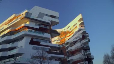 Milan, İtalya - 04 / 04 / 2020: Yeni ticari ve yerleşim alanındaki modern mimari ve kule. Milan Şehir Hayatı. Betondan, camdan ve ahşaptan yapılmış modern evler. Lombardiya. Gün batımı. 