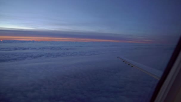 坐着飞机飞行 飞机照明灯的日出或日落 飞机的机翼在棉花云中飞行 从飞机的窗户看风景 坐飞机旅行 多彩的天空 — 图库视频影像