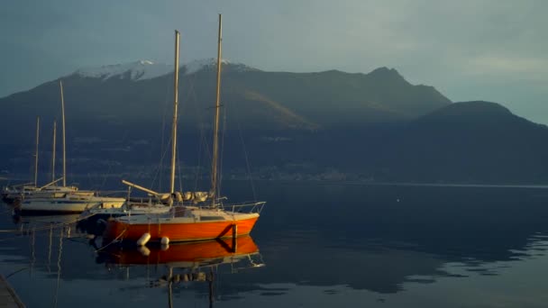 帆船停泊在意大利科莫湖畔的海岸外 日落之前越过高山山峰的地平线 电影框架 浪漫的气氛 平静和安抚的场景 — 图库视频影像