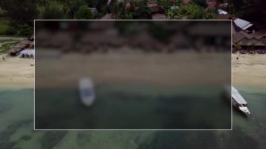 Gili Air, Endonezya: İnsansız hava aracı ile bir adanın vurulması. Adanın çerçevesinde, sahil bölgesinde, kıyıya demir atmış nakliye gemileri. Panoramik görüntüler. Bulutlu hava. 