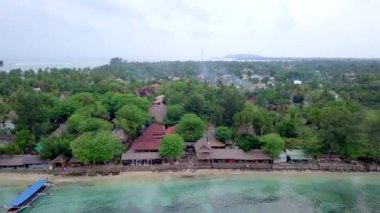 Gili Air, Endonezya: İnsansız hava aracı ile bir adanın vurulması. Adanın çerçevesinde, sahil bölgesinde, kıyıya demir atmış nakliye gemileri. Panoramik görüntüler. Bulutlu hava. 