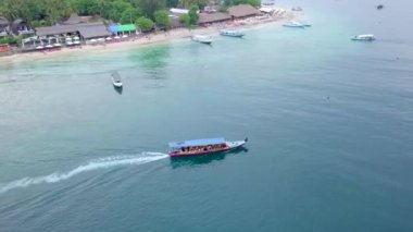 Gili Air, Endonezya: İnsansız hava aracı ile bir adanın vurulması. Adanın çerçevesinde, sahil bölgesinde, kıyıya demir atmış nakliye gemileri. Panoramik görüntüler. Bulutlu hava. 
